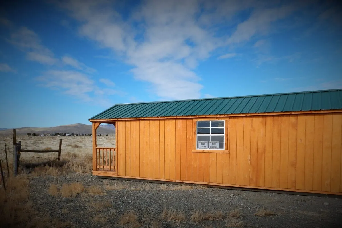 A post-frame barn cabin with a metal roof in an open field